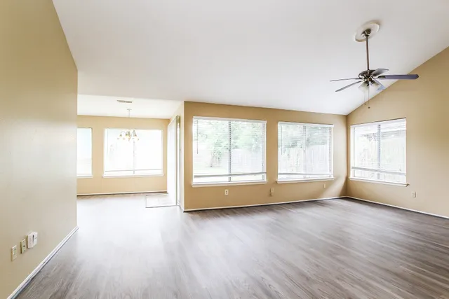 a view of an empty room with a window and wooden floor