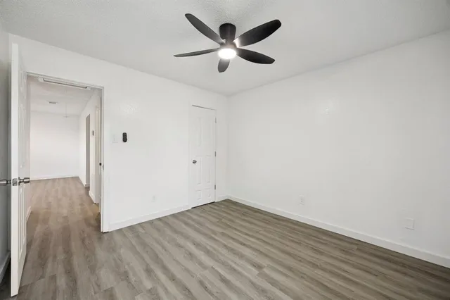 an empty room with wooden floor and ceiling fan