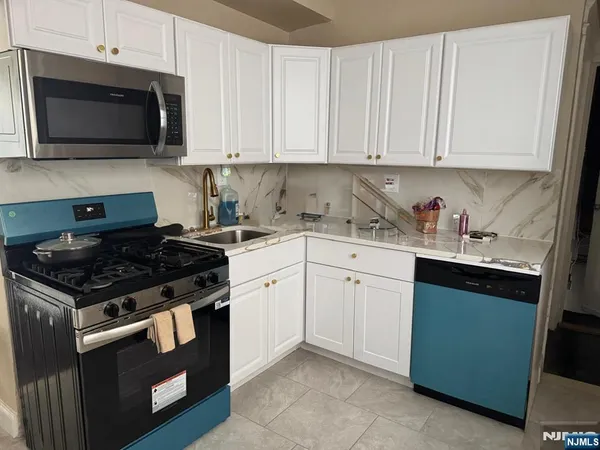 a kitchen with granite countertop white cabinets and stainless steel appliances