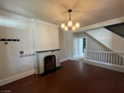 a view of a livingroom with a fireplace a ceiling fan and wooden floor
