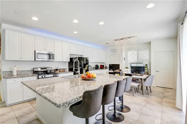 a kitchen with stainless steel appliances granite countertop a table chairs sink refrigerator and cabinets