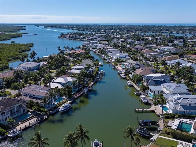 an aerial view of ocean and residential houses with outdoor space