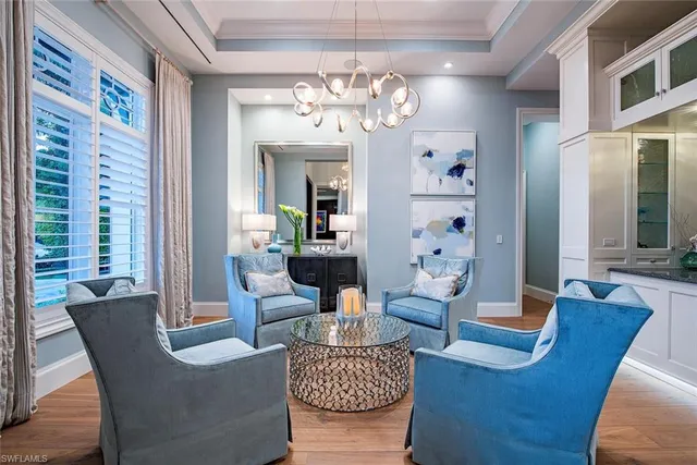 a living room with furniture a chandelier and a large mirror