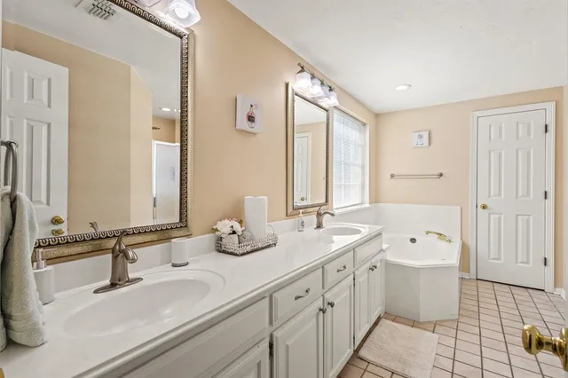 a bathroom with a double vanity sink a mirror and a bathtub