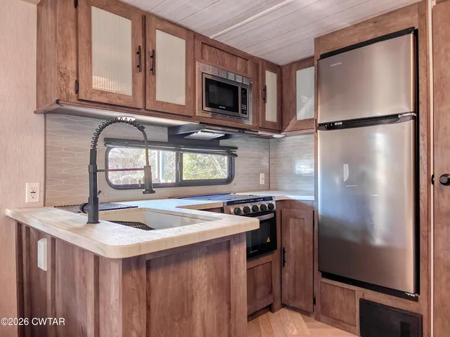 a kitchen with stainless steel appliances granite countertop a refrigerator a stove a sink and a microwave