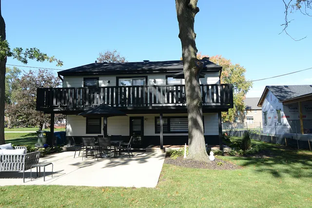 a view of a house with a yard fire pit and a large tree