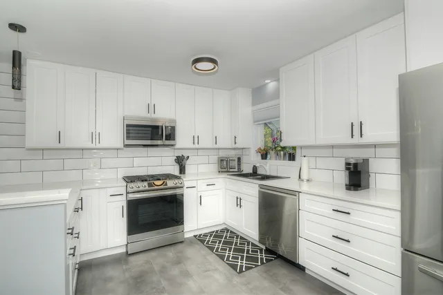 a kitchen with white cabinets stainless steel appliances and sink