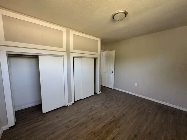 a view of an empty room with wooden floor and closet