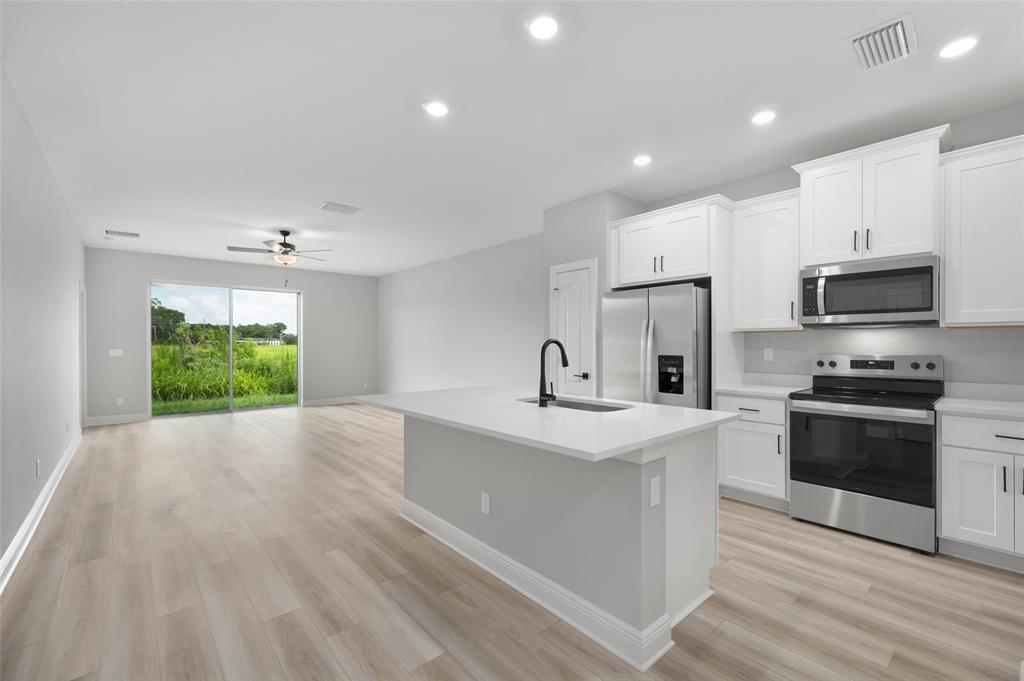 1813 Gaiety Way Fort Pierce, FL 34947 - Photo 6 of 16 a kitchen with stainless steel appliances granite countertop a sink a stove a refrigerator and a oven with wooden floor