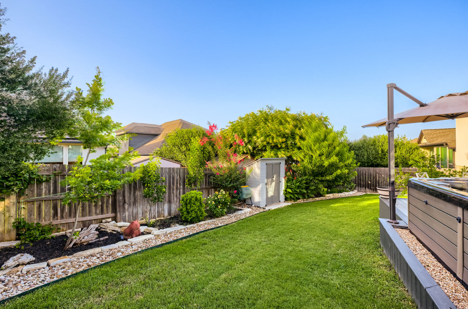 621 Rancho Sienna Loop Georgetown, TX 78628 - Photo 26 of 28 A fenced backyard offers a hot tub, mature landscaping, and ample lawn space.
