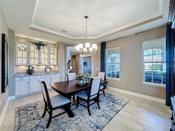 a dining room with wooden floor a chandelier a wooden table and chairs