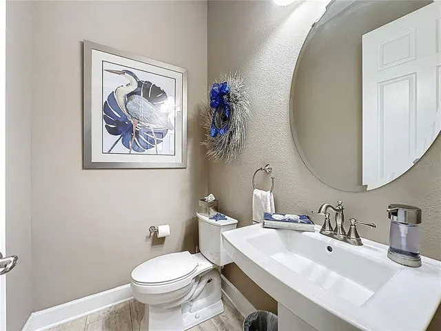 a bedroom with a bed a chair and potted plant on the dresser