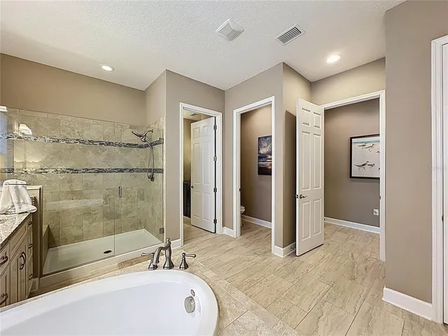 a utility room with stainless steel appliances granite countertop a stove and a refrigerator with white cabinets