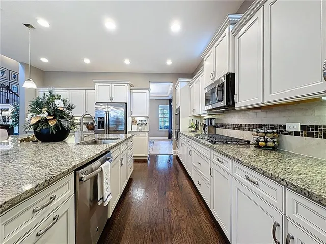 a large kitchen with stainless steel appliances granite countertop a lot of counter space a sink and dishwasher a stove top oven with wooden floor