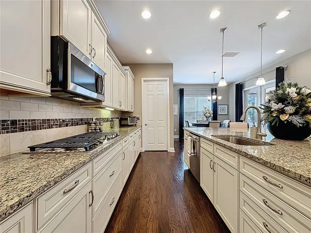 a large kitchen with stainless steel appliances granite countertop a lot of counter space a sink and cabinets
