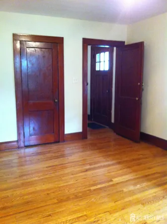 a view of empty room with window and wooden floor