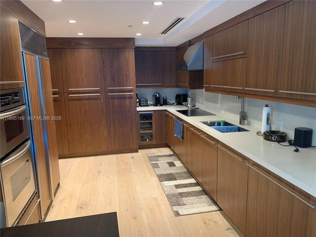 a kitchen with stainless steel appliances kitchen island wooden cabinets a sink and a refrigerator