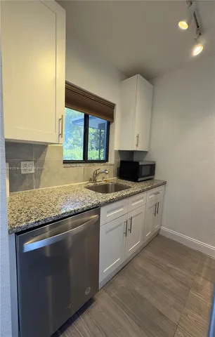 a kitchen with granite countertop cabinets stainless steel appliances a sink and a window