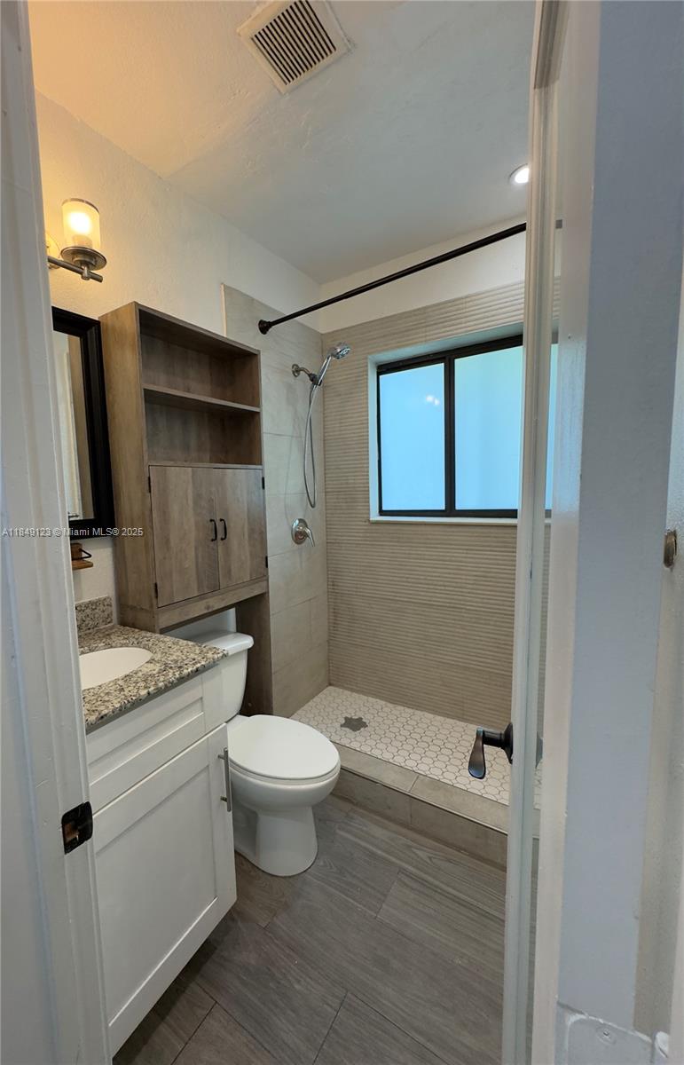 560 Northeast 69th Street, Unit 1 Miami, FL 33138 - Photo 16 of 23 a bathroom with a granite countertop toilet a sink and shower