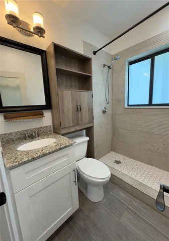 a bathroom with a granite countertop sink toilet and shower