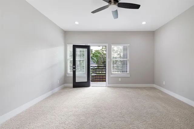 an empty room with ceiling fan and windows