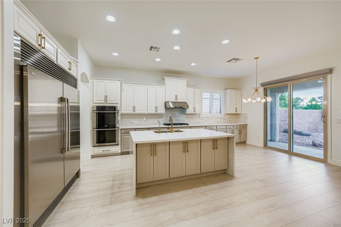 Kitchen featuring backsplash, stainless steel appliances, pendant lighting, recessed lighting, and a chandelier