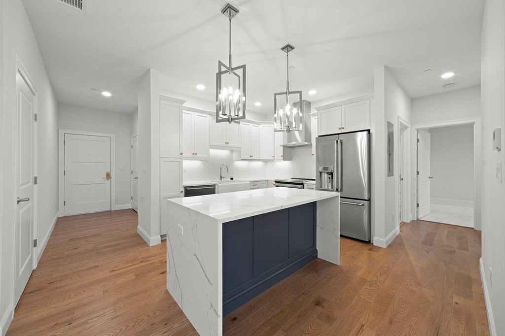 60 Coppersmith Way, Unit 404 Canton, MA 02021 - Photo 8 of 42 a kitchen with stainless steel appliances a refrigerator a sink dishwasher a stove and white cabinets with wooden floor