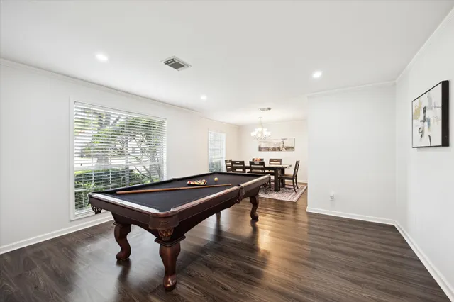 a room with wooden floor pool table and windows