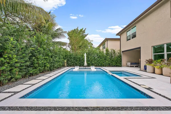 a view of swimming pool with chairs in front of house