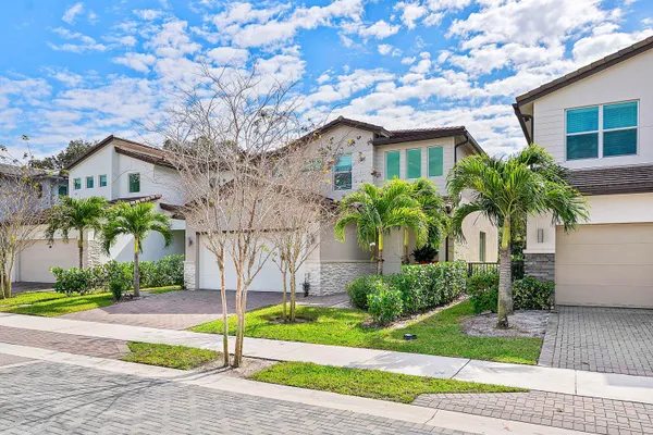 a front view of a house with a yard and potted plants