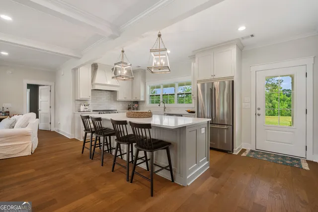 a kitchen with stainless steel appliances granite countertop a table chairs and a refrigerator