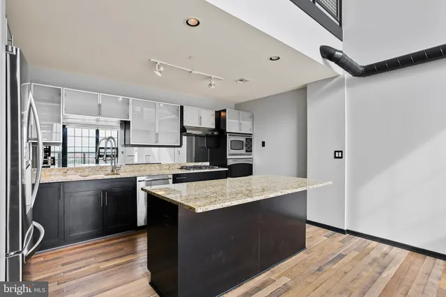 a kitchen with stainless steel appliances granite countertop a kitchen island a stove and a refrigerator