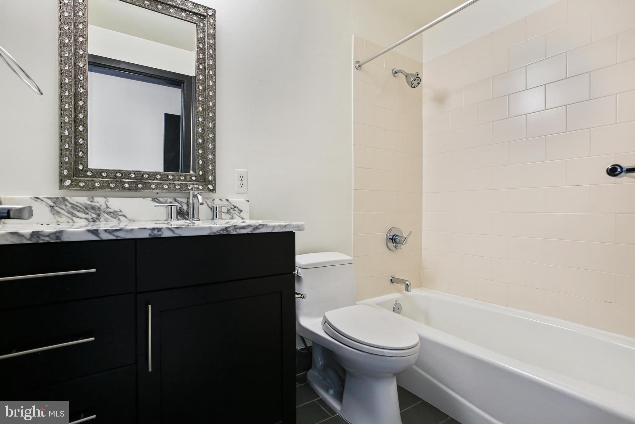 1200 Steuart Street, Unit 1913 Baltimore, MD 21230 - Photo 35 of 39 a bathroom with a bathtub sink vanity mirror and toilet