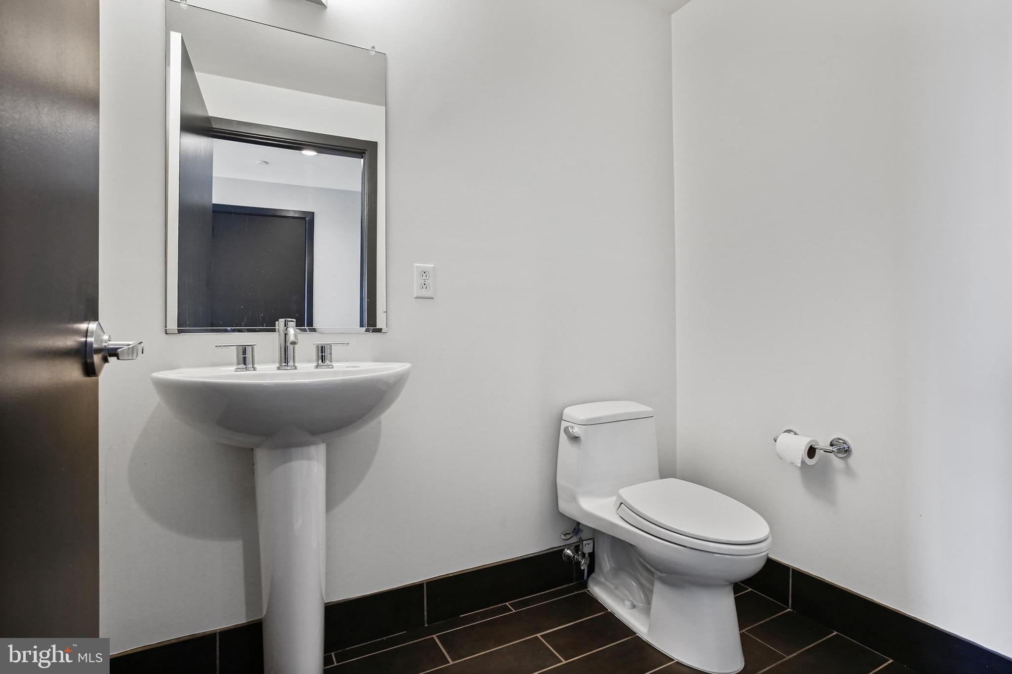 1200 Steuart Street, Unit 1913 Baltimore, MD 21230 - Photo 36 of 39 a bathroom with a sink toilet and mirror