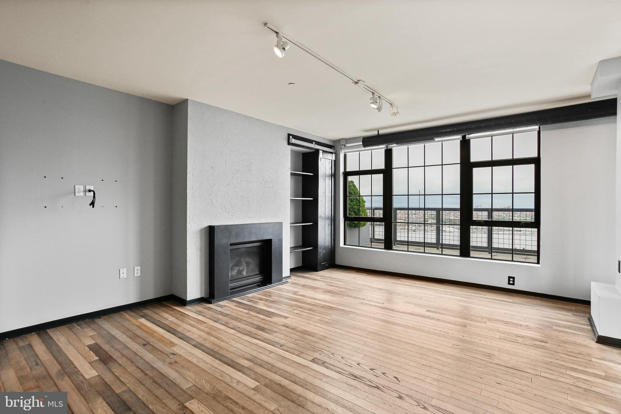 1200 Steuart Street, Unit 1913 Baltimore, MD 21230 - Photo 4 of 39 wooden floor fireplace and windows in an empty room