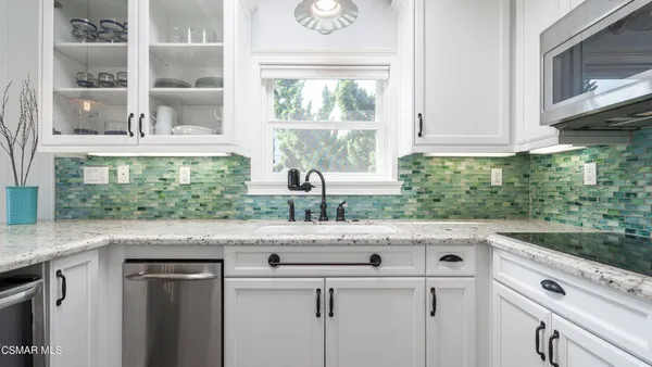 a kitchen with stainless steel appliances white cabinets and a window