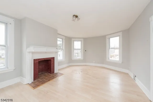 a view of an empty room with window and fire place