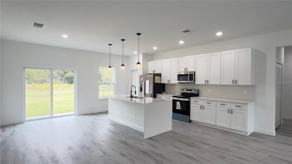 16734 Southwest 18th Avenue Road Ocala, FL 34473 - Photo 6 of 36 a kitchen with stainless steel appliances granite countertop a refrigerator a stove top oven a sink and dishwasher with wooden floor