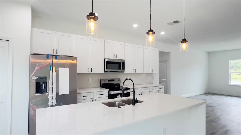 16734 Southwest 18th Avenue Road Ocala, FL 34473 - Photo 7 of 36 a kitchen with stainless steel appliances a stove a sink a refrigerator a center island a stove and a cabinets