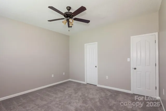 an empty room with a ceiling fan and a window
