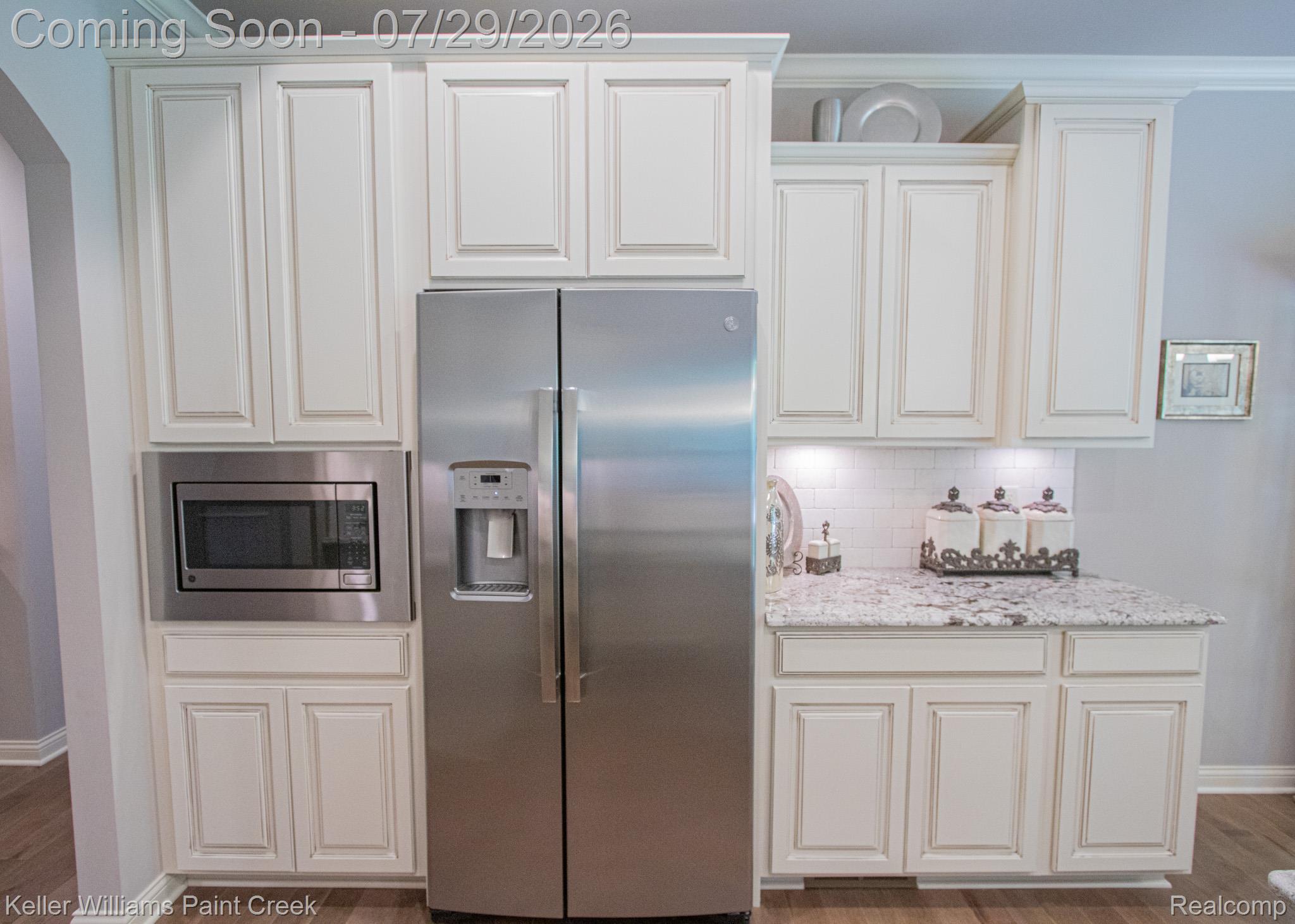 49118 Ridgeview Drive Macomb, MI 48044 - Photo 18 of 57 Kitchen featuring off-white cabinetry with crown molding, stainless steel refrigerator, built-in microwave, light-toned patterned countertop, and subway tile backsplash