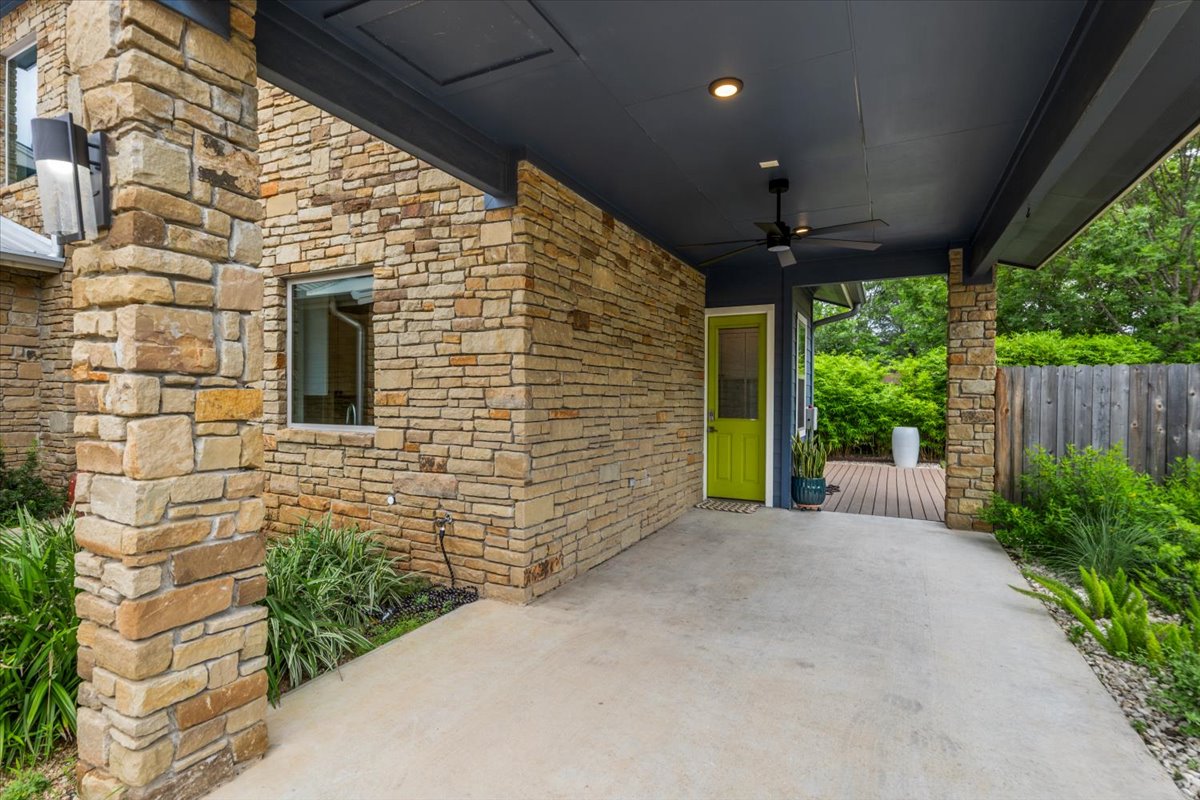 913 Stobaugh Street, Unit B Austin, TX 78757 - Photo 4 of 40 A vibrant green side door welcomes you to this stone-clad home, nestled among lush greenery.