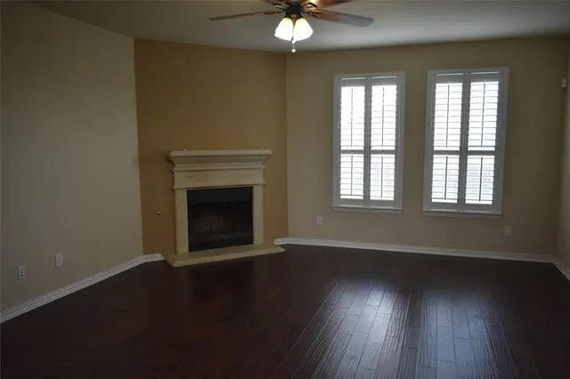 an empty room with wooden floor fireplace and windows