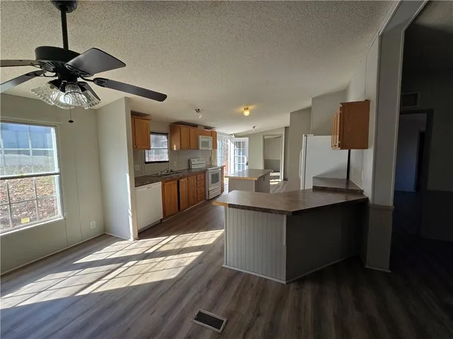 a kitchen with stainless steel appliances a refrigerator a stove a sink and white cabinets with wooden floor