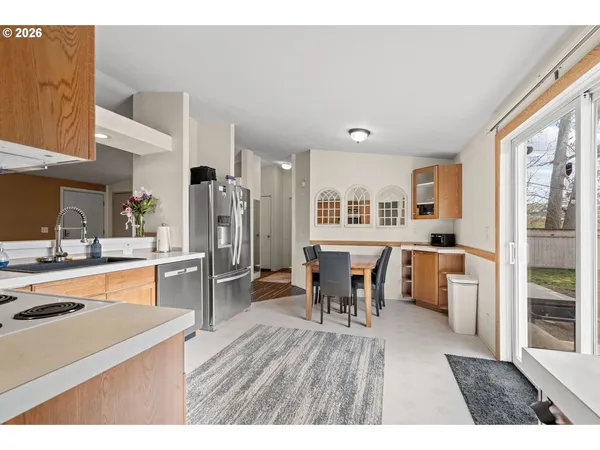 a open kitchen with stainless steel appliances granite countertop a refrigerator a stove a sink a dining table and chairs with wooden floor
