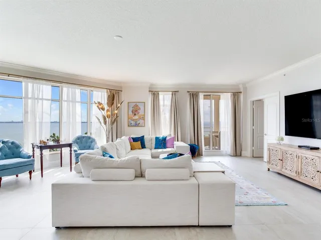 a living room with stainless steel appliances kitchen island granite countertop a refrigerator a stove and a dining table with wooden floor