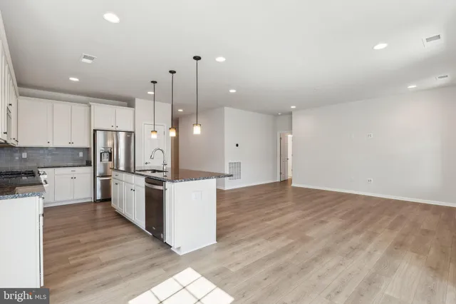 a large kitchen with granite countertop a large counter top stainless steel appliances and cabinets