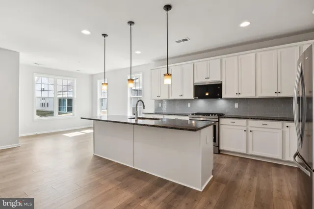 a kitchen with stainless steel appliances granite countertop a sink a stove a microwave and a wooden floor