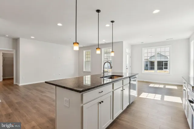 a kitchen with stainless steel appliances granite countertop a sink a oven a dining table and chairs with wooden floor