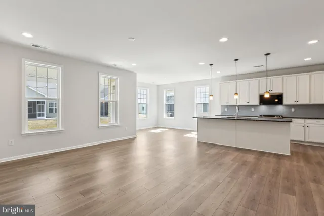 a large kitchen with stainless steel appliances granite countertop a large counter top a wooden floor and a window